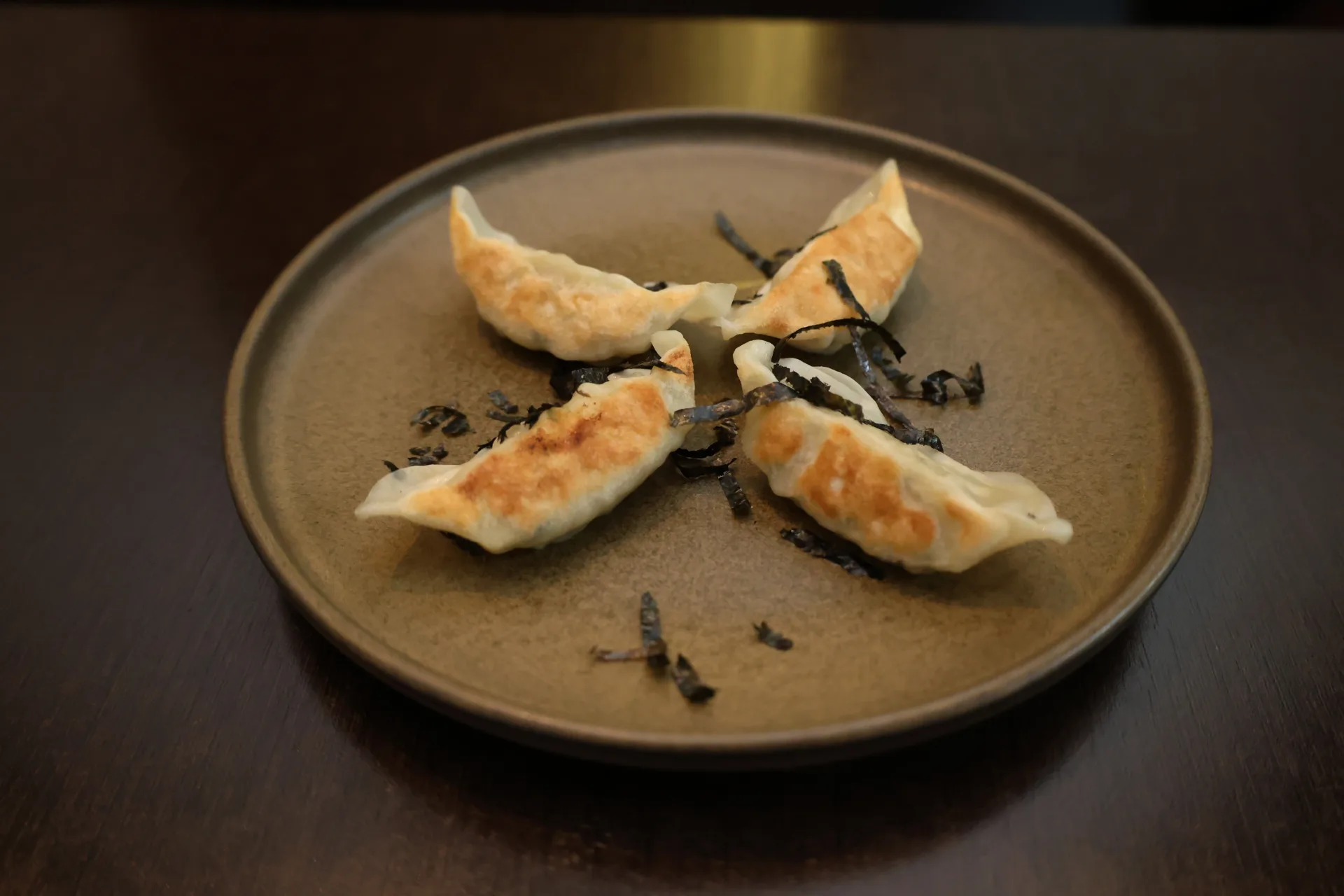 Pan-seared gyoza arranged on a ceramic plate at Koko
