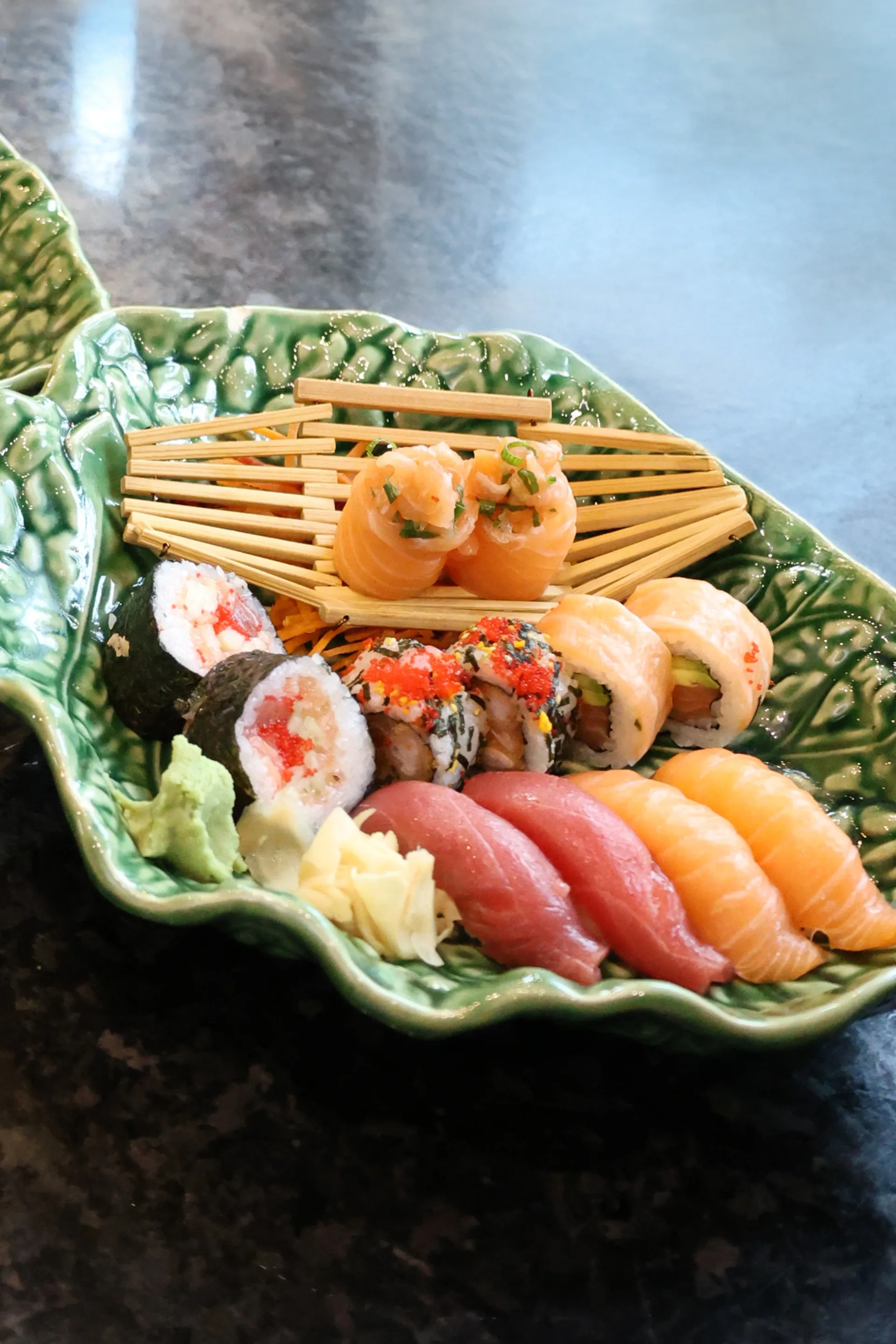 Assorted nigiri and sushi arranged on a green ceramic platter at Koko
